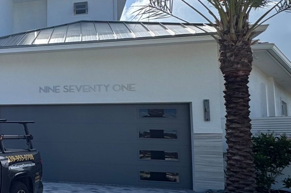 Completed modern gray flush-panel garage door with contemporary side windows and the home's address, installed by Eddie's Garage Door in Southwest Florida