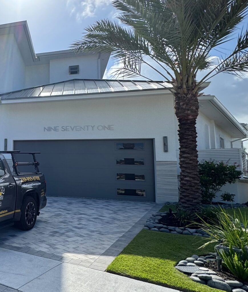 Front view of a modern two-story Southwest Florida home with a new gray flush-panel garage door and contemporary side windows installed by Eddie's Garage Door
